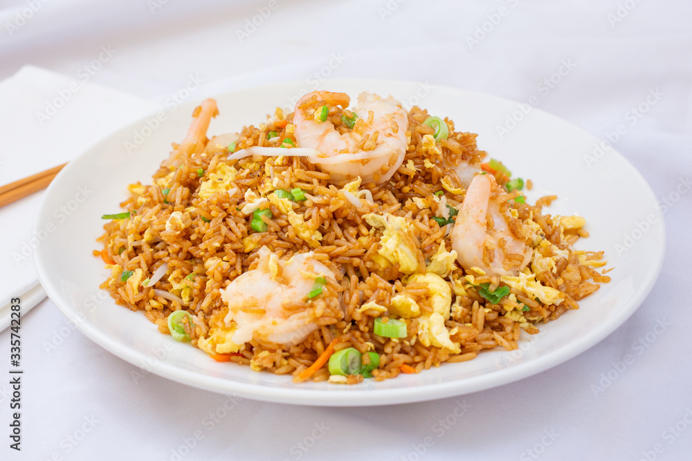 A view of a plate of Chinese shrimp fried rice, in a restaurant or kitchen setting. A view of a plate of Chinese shrimp fried rice, in a restaurant or kitchen setting.