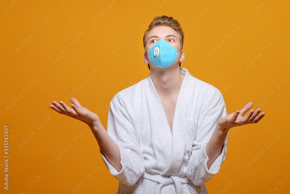 young man in medical mask and housecoat in quarantine on yellow orange background, emotions, young man in medical mask and housecoat in quarantine on yellow orange background, emotions,