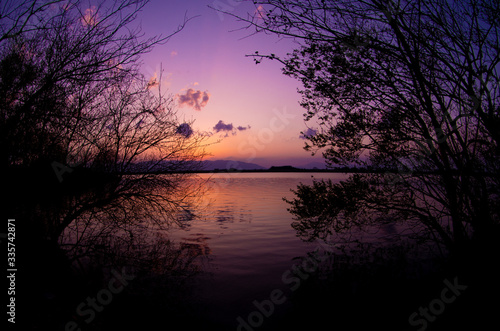 夕焼けの水面と草木 © SUGICK