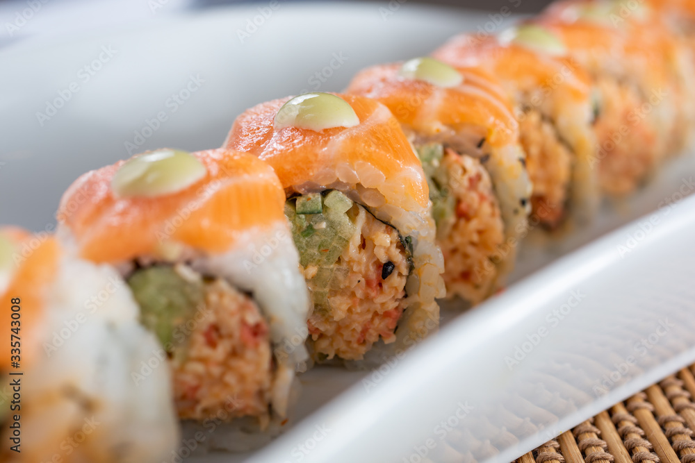 A closeup view of the middle portion of an orange dragon roll sushi plate, in a restaurant or kitchen setting.