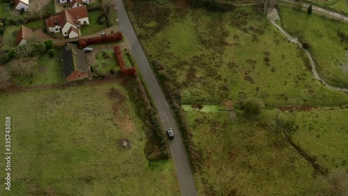 Aerial view of Autonomous driving car in a town in England. Residential houses, green landscape and trees in the background. photo