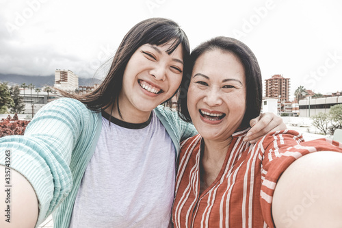 Happy asian mother and daughter taking selfie portrait photo for mother's day fest - Family people having fun with technology trends - Love and summer concept - Focus on faces