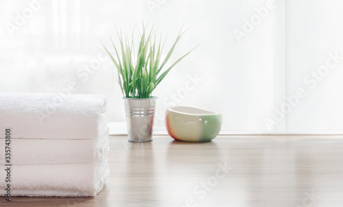 Folded clean white towels and houseplant on wooden table.