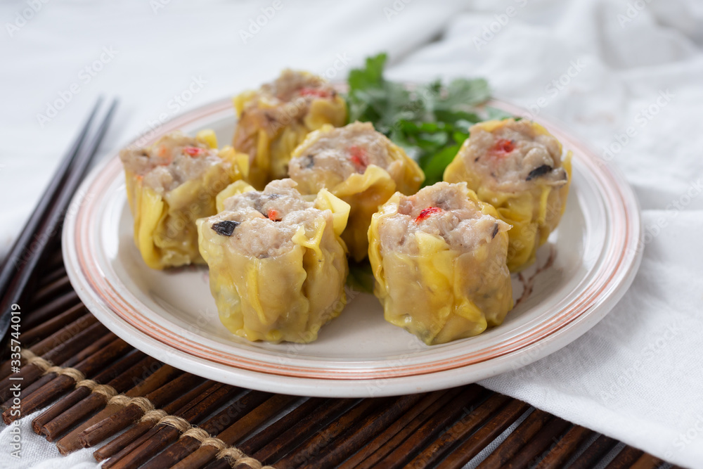 A view of a plate of siu mai dumplings, in a restaurant or kitchen setting.