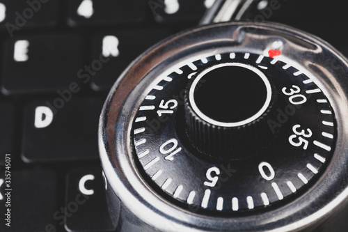 Strong steel coded lock, padlock laying on a black laptop keyboard, macro, closeup IT security policies, passwords codes management, account and network securing and protection simple abstract concept