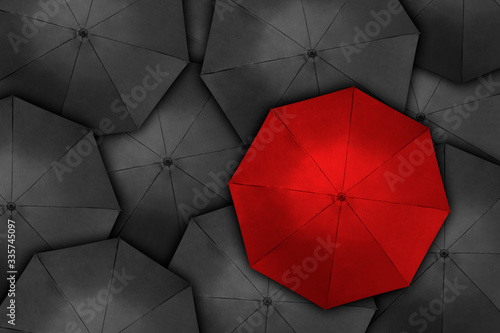 Red umbrella over many dark ones