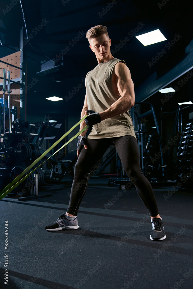 Fototapeta premium Muscular man training back with resistance band.