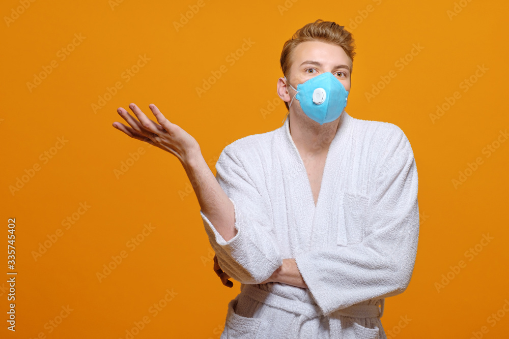 young man in medical mask and housecoat in quarantine on yellow orange background, emotions, young man in medical mask and housecoat in quarantine on yellow orange background, emotions,