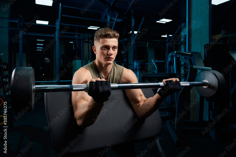 Muscular man training biceps with barbell. Muscular man training biceps with barbell.