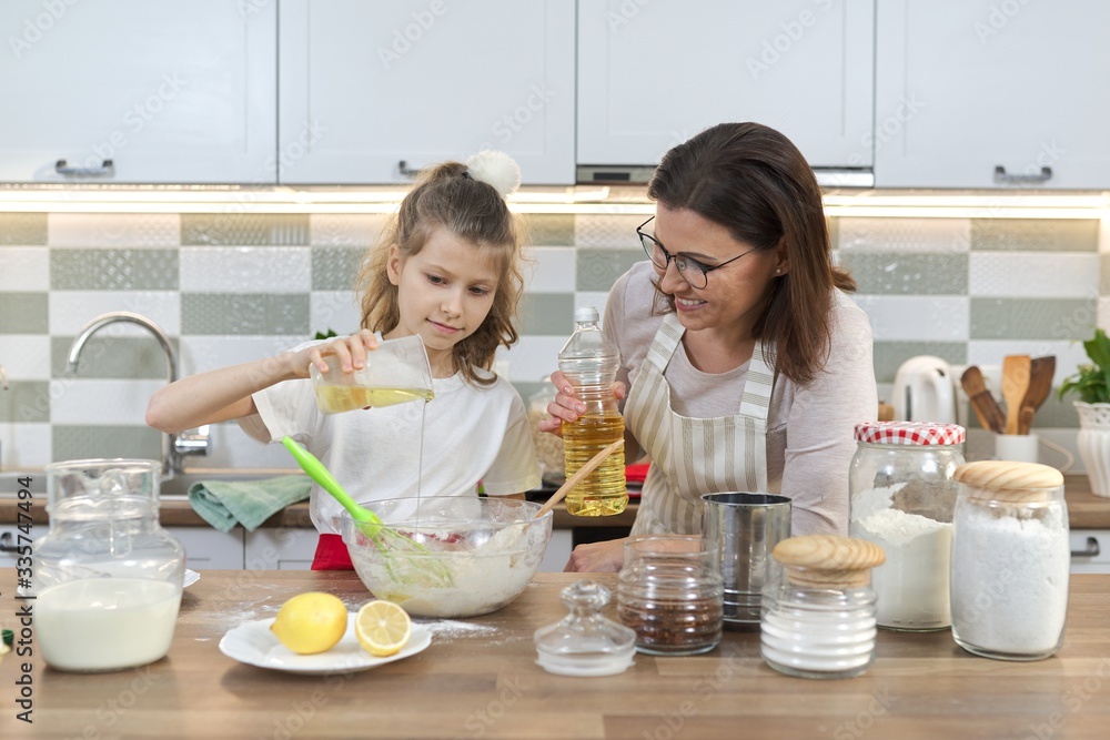 Mother and daughter child together at home kitchen preparing cookies Mother and daughter child together at home kitchen preparing cookies