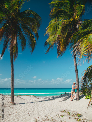 Fototapeta Naklejka Na Ścianę i Meble -  younge man stay near the palm on the ocean beach of tropical island