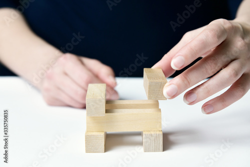 Women's hands are building a tower of wooden pieces. Conceptual photo of the construction.