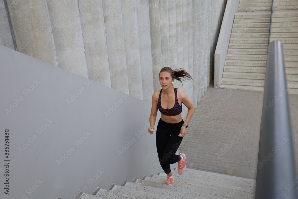 Runner athlete running on stairs. Woman fitness is jogging oudoors