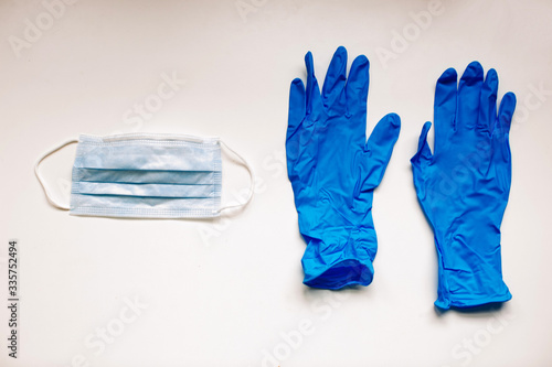 Virus protection surgical face mask and dark blue gloves for coronavirus placed on white background with copy space