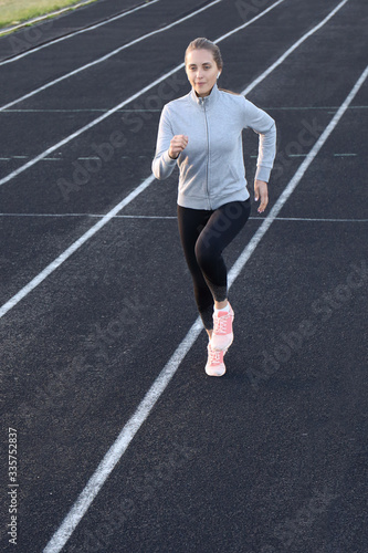 Runner athlete running on athletic track training her cardio in stadium. Jogging at fast pace for competition
