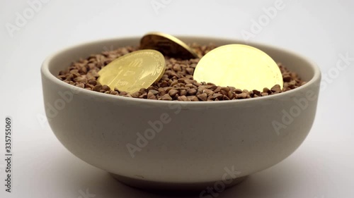 Buckwheat groats and bitcoin coins in a deep cup. Footage. 360 rotation.