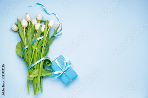 Gift and beautiful flowers on color background