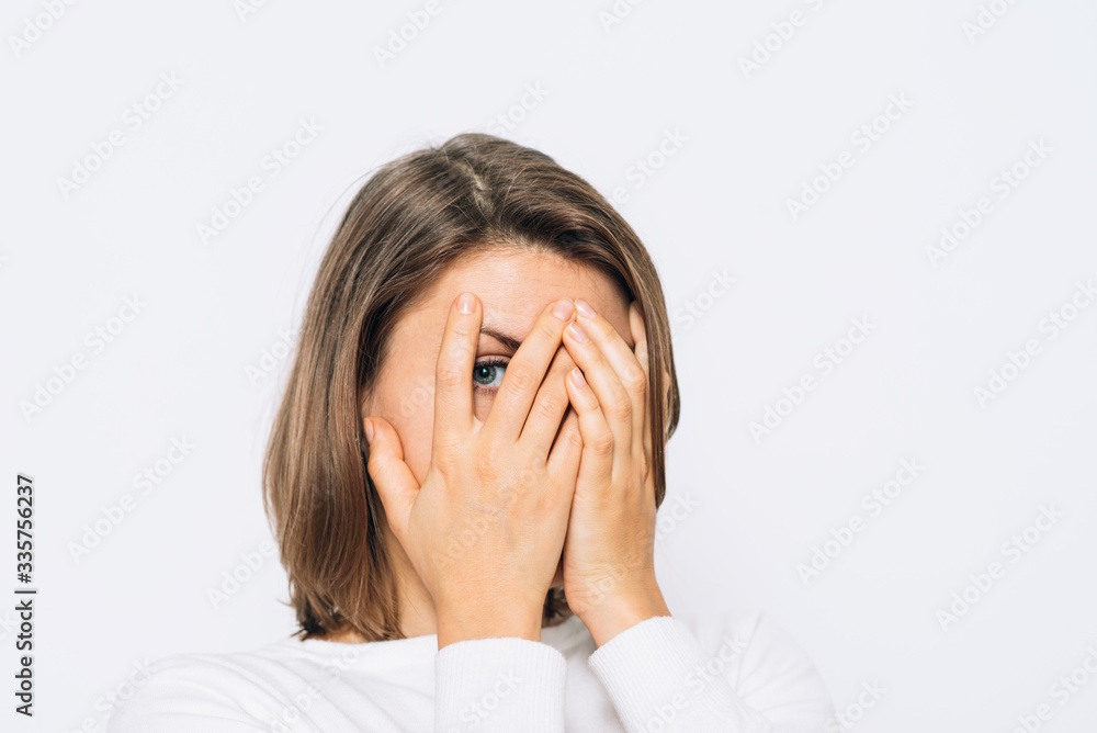 The woman covers her face with her hands and peeps The woman covers her face with her hands and peeps