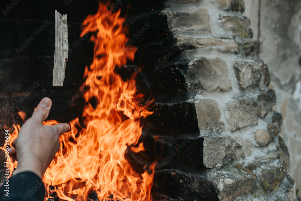 Obraz premium hand throwing a piece of firewood on fire flames