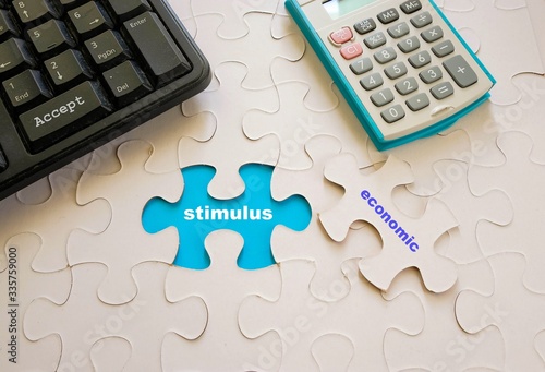 Conceptual economic stimulus to financial assist to business and citizens to weather impact of virus out or crisis. Keyboard calculator and jigsaw puzzle with texts. Focus on missing piece space.