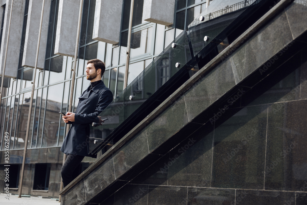 Photo of smiling businessman in coat and turtleneck with bagpack, talking on the phone Photo of smiling businessman in coat and turtleneck with bagpack, talking on the phone