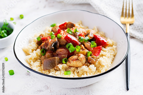 Bulgur and sauteed chicken, mushrooms, eggplants, paprika and tomatoes in a white bowl.