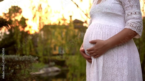 Pregnant woman feeling happy with new life at garden home while take care of her child. The young expecting mother holding baby in pregnant belly. Maternity prenatal care and woman pregnancy concept. photo