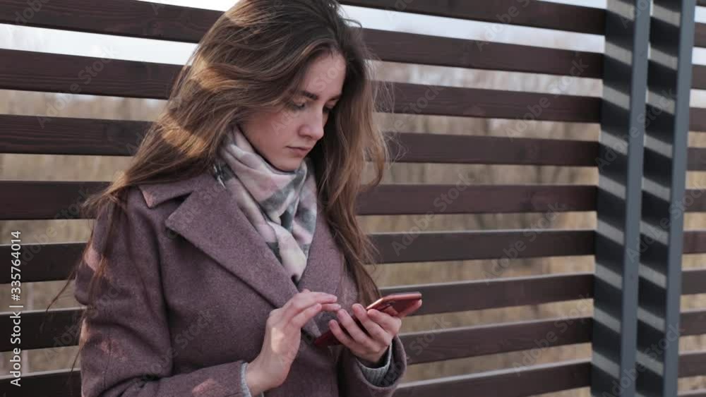 Young girl looks for something in her phone and gets upset, in the park Young girl looks for something in her phone and gets upset, in the park