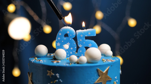 Birthday cake number 65 stars sky and moon concept, blue candle is fire by lighter. Copy space on right side of screen. Close-up