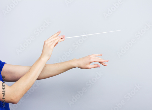 Female hands isolated on gray. Woman conductor. Female hands with a conductors  baton.