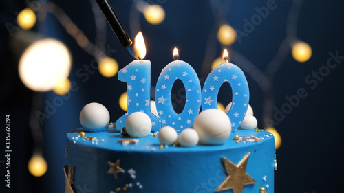 Birthday cake number 100 stars sky and moon concept, blue candle is fire by lighter. Copy space on right side of screen. Close-up