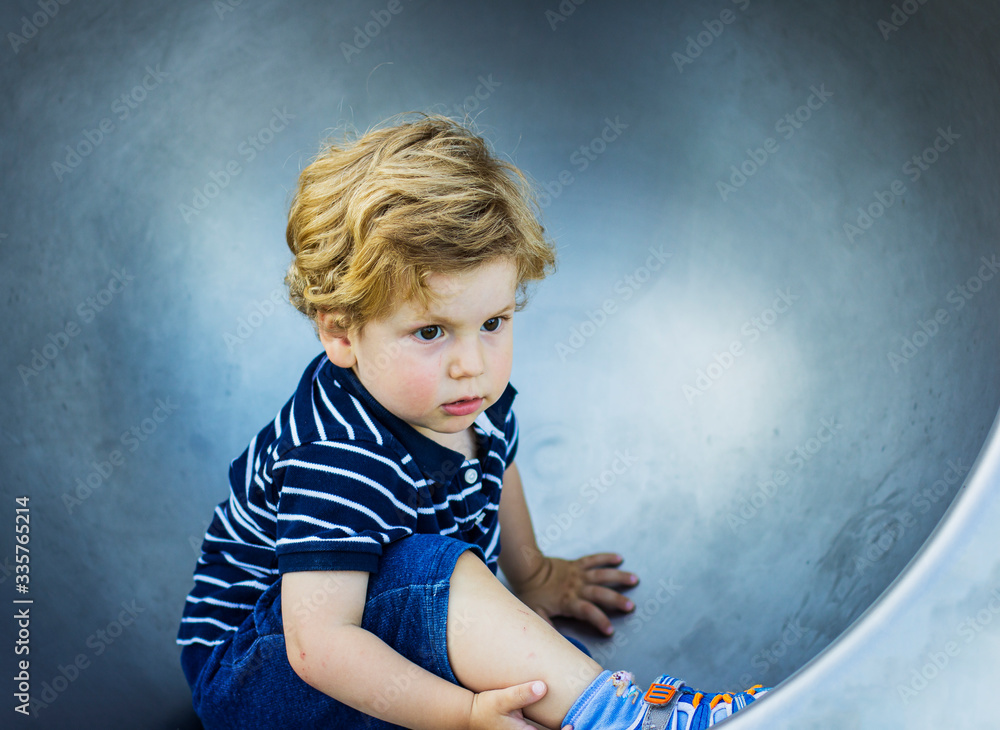 Fototapeta premium Portrait of a child on an iron swing. A little boy walks alone in the yard.