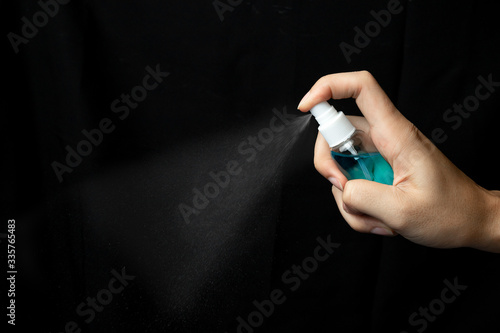 Antiseptic spray or sanitizer in male hand. Coronavirus Disease (Covid-19) prevention concept. Picture isolated on black background.