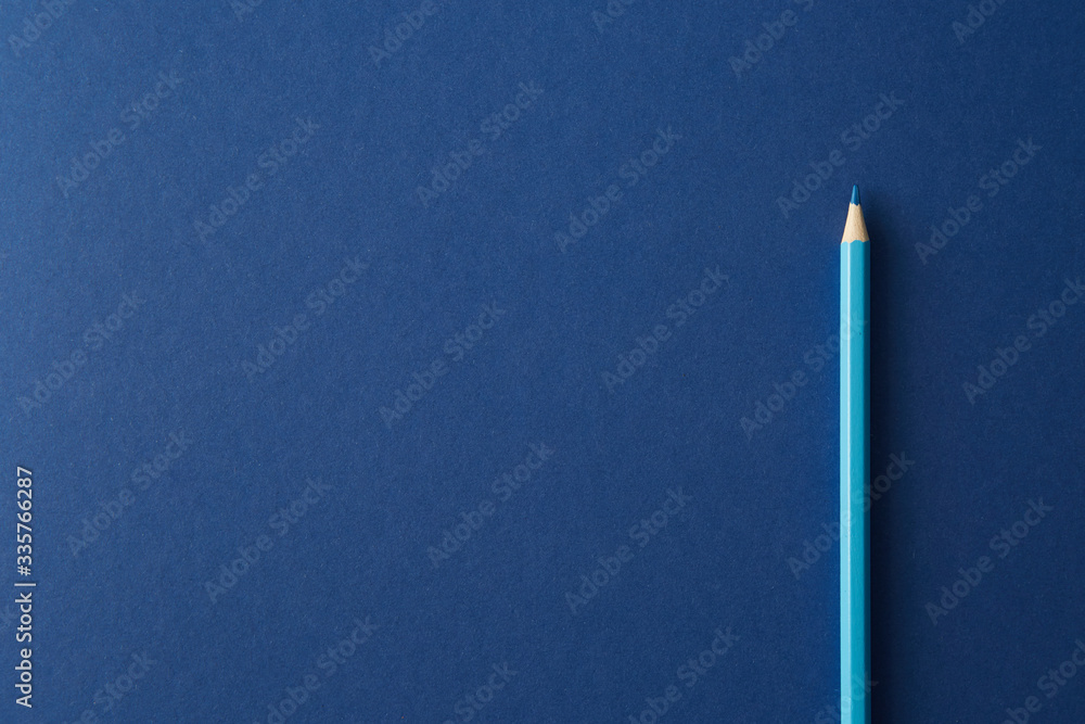 Blue colored pencil lying on a bright blue background Blue colored pencil lying on a bright blue background