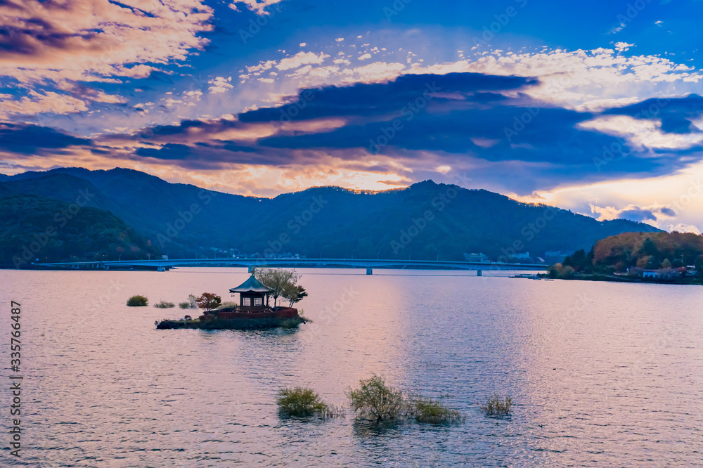 Japan. Panorama of the lake Kawaguchiko. Arbor on a small island in the middle of the lake. Autumn landscape of the Japanese lake. Sunset over the lake Kawaguchiko. Japanese-style gazebo