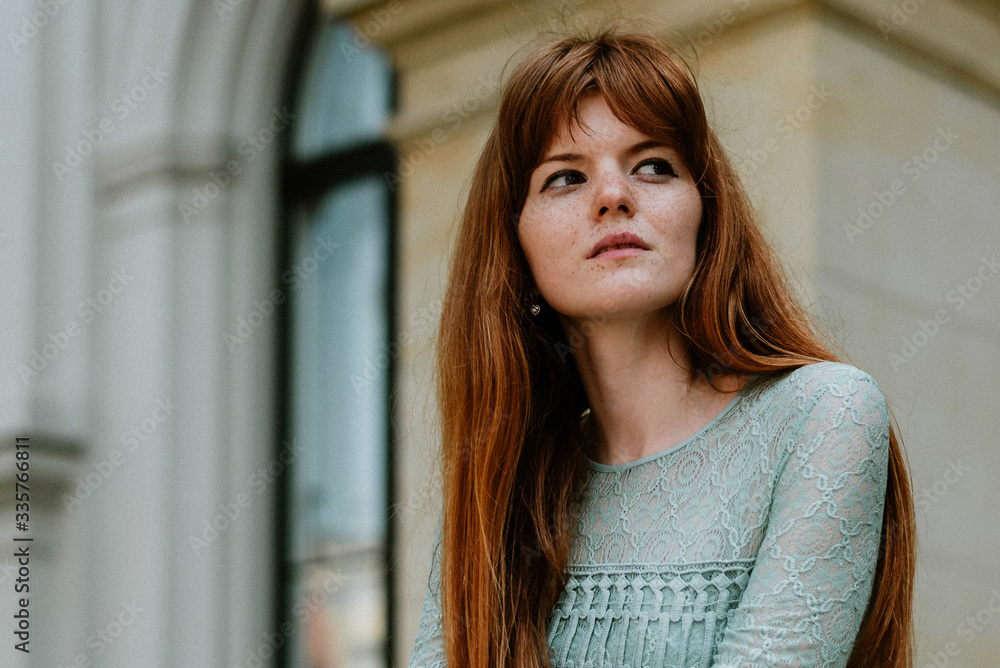 Stylish urban young redhair woman in a fashionable green dress posing in the street. European modern cute model girl enjoys a walk in the city. Spring fashion. Stylish urban young redhair woman in a fashionable green dress posing in the street. European modern cute model girl enjoys a walk in the city. Spring fashion.