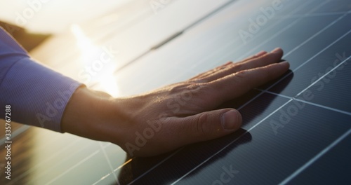 Close up of an young engineer hand is checking an operation of sun and cleanliness of photovoltaic solar panels on a sunset.Concept:renewable energy, technology,electricity,service, green,future photo