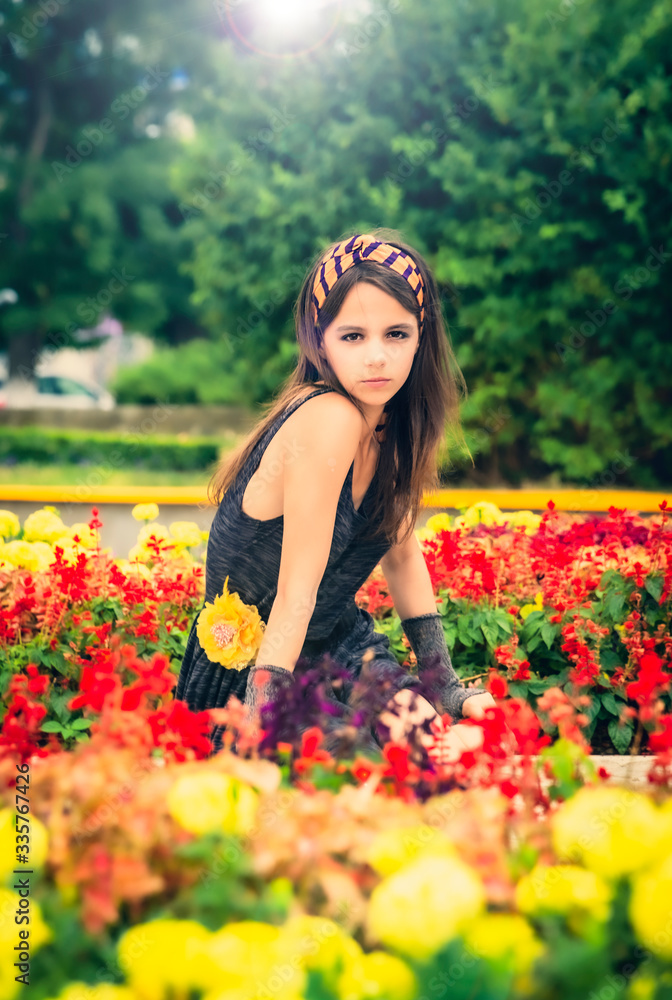 cheerful girl at the flower decorations, the theme of beautiful vibrant women. The girl next to the flowers in the city park. Urban landscaping cheerful girl at the flower decorations, the theme of beautiful vibrant women. The girl next to the flowers in the city park. Urban landscaping