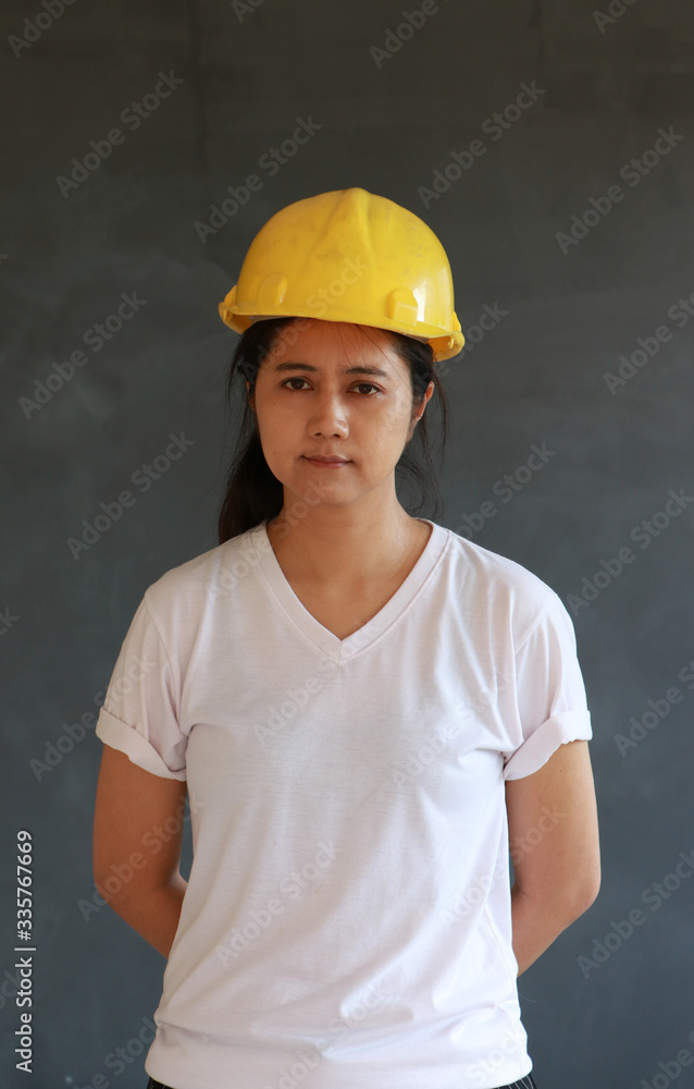 Female civil engineer with yellow helmet and wear white T-shirt on dark grey background. Female civil engineer with yellow helmet and wear white T-shirt on dark grey background.