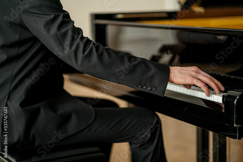 cropped unrecognizable male in suit playing piano on a stage. handsome guy gracefully play piano, practice before performance © alfa27