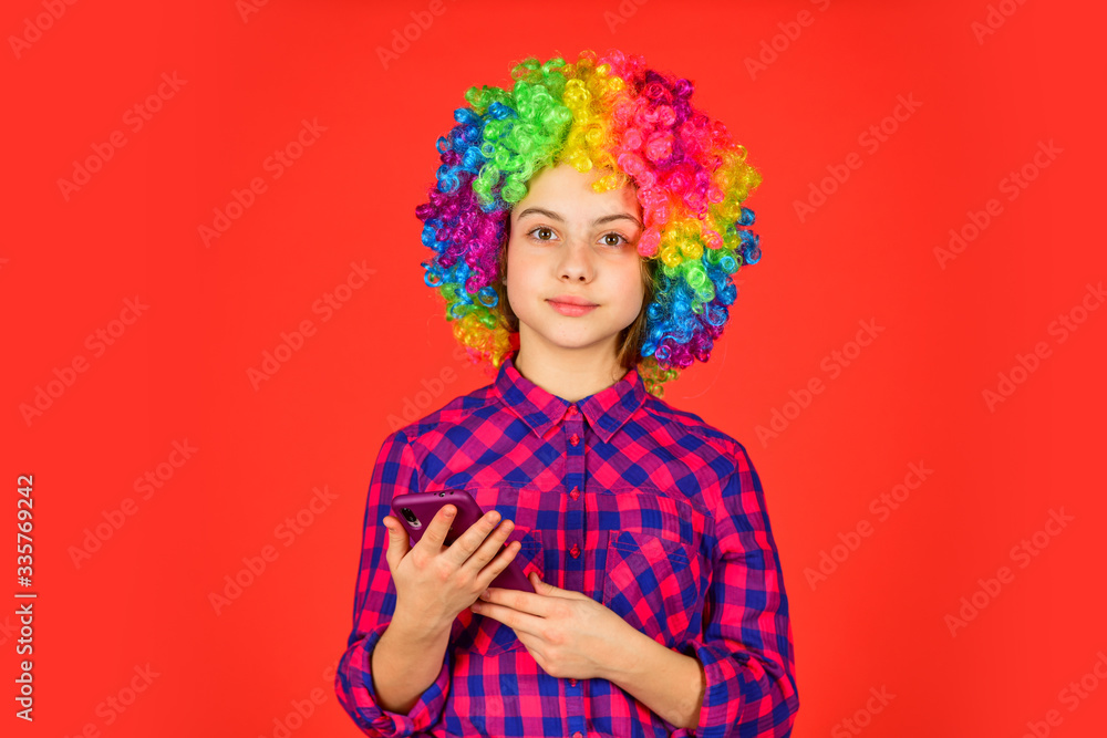 small girl colorful wig use smartphone. positive and cheerful