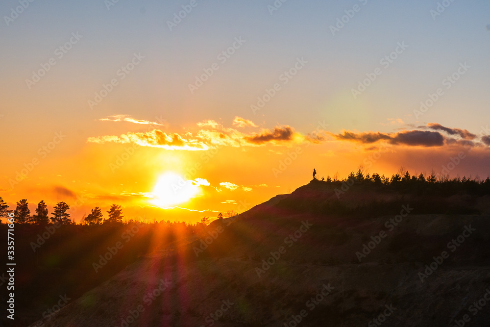 The man spread his hands to the sides towards the sun. Active outdoor recreation. The winner at the top of the mountain is looking at dawn. The man spread his hands to the sides towards the sun. Active outdoor recreation. The winner at the top of the mountain is looking at dawn.