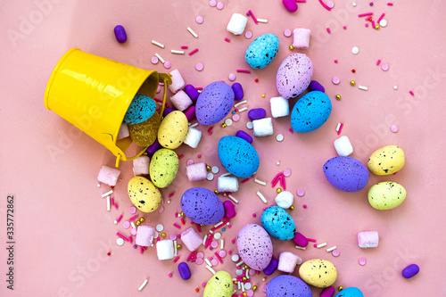 Decoration Happy Easter holiday background concept. Colorful bunny eggs in a yellow bucket on pink desk. Egg hunt.