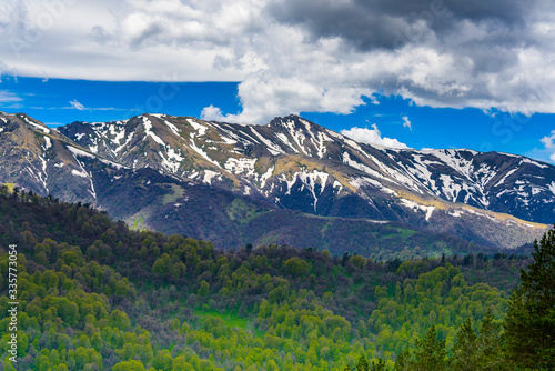 Beautiful mountain panorama with lush greens, blue skies, and puffy clouds