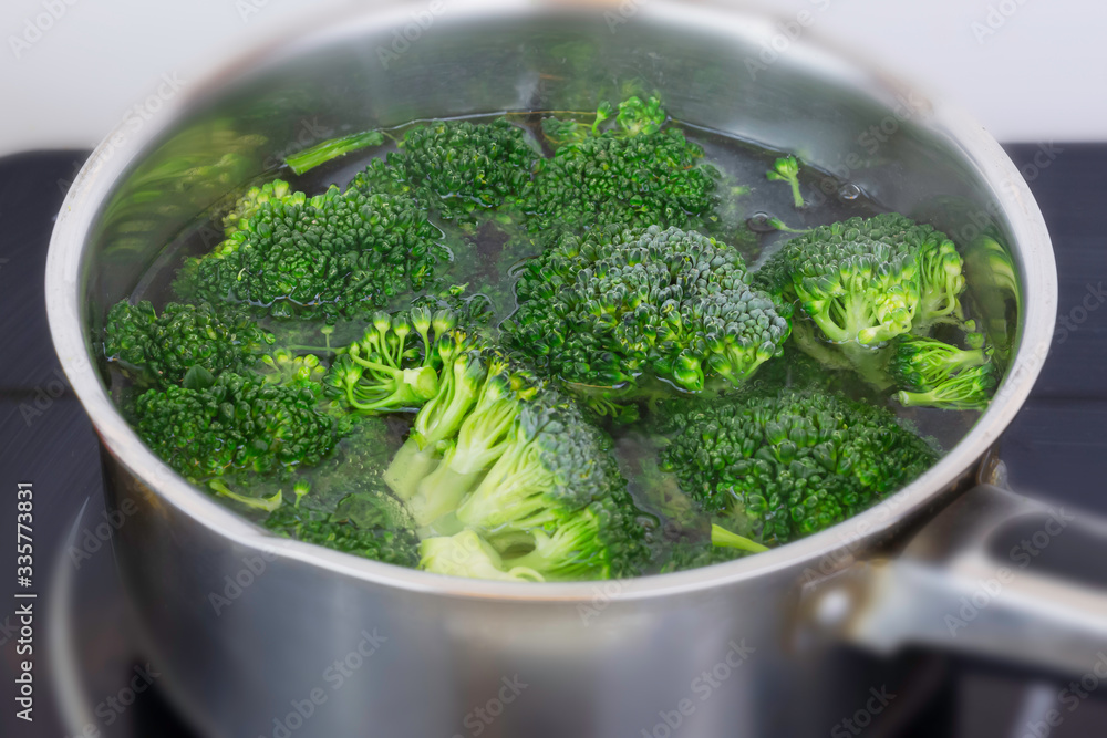 Cooking organic broccoli florets in small stainless steel pan in domestic kitchen.Vegan meal preparation.Healthy eating.Popular green vegetable.Healthy diet and lifestyle. Cooking organic broccoli florets in small stainless steel pan in domestic kitchen.Vegan meal preparation.Healthy eating.Popular green vegetable.Healthy diet and lifestyle.