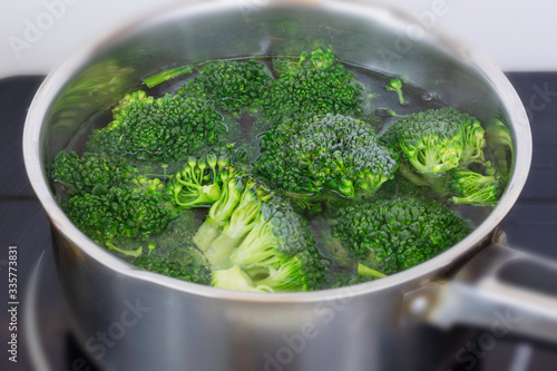 Cooking organic broccoli florets in small stainless steel pan in domestic kitchen.Vegan meal preparation.Healthy eating.Popular green vegetable.Healthy diet and lifestyle.