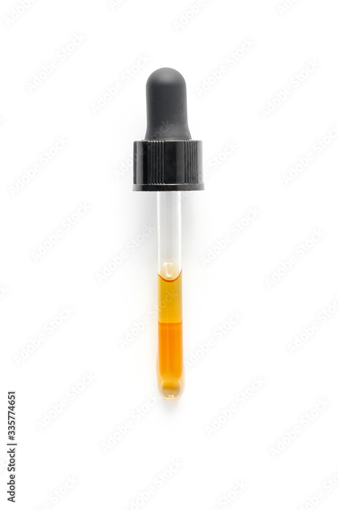 Pipette dropping essential black cumin seeds Nigella Sativa on white background