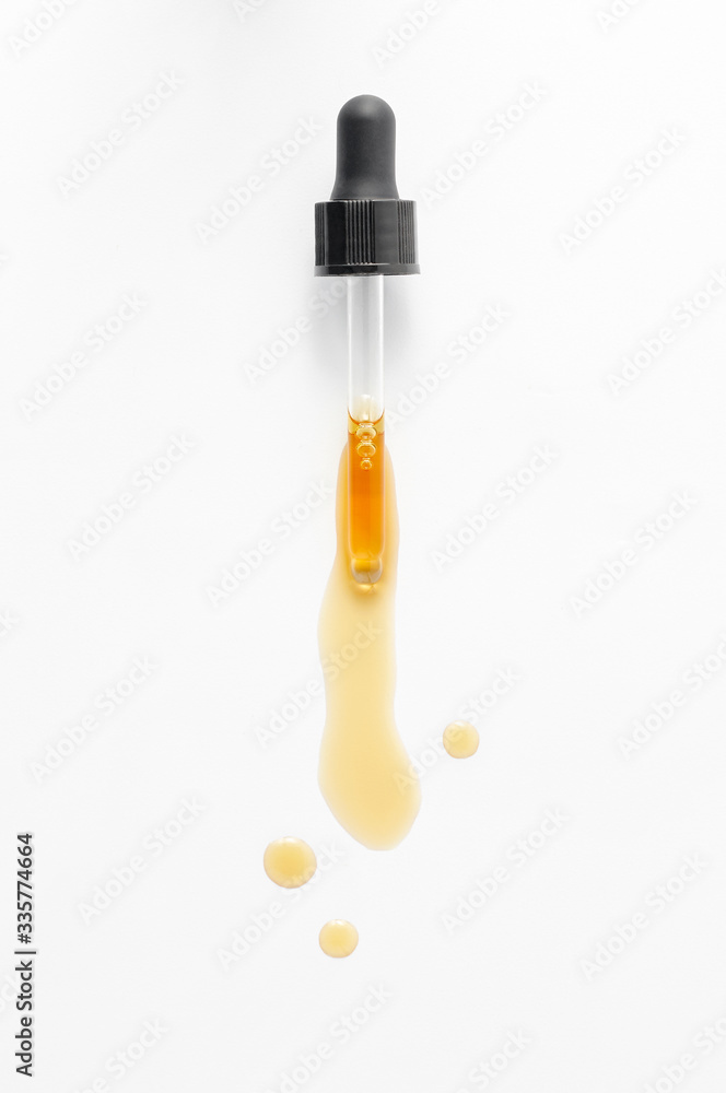 Pipette dropping essential black cumin seeds Nigella Sativa on white background