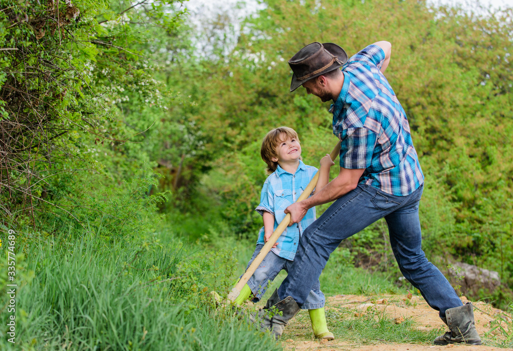 Fototapeta premium Spirit of adventures. Adventure hunting for treasures. Little helper in garden. Cute child in nature having fun cowboy dad. Find treasures. Little boy and father with shovel looking for treasures