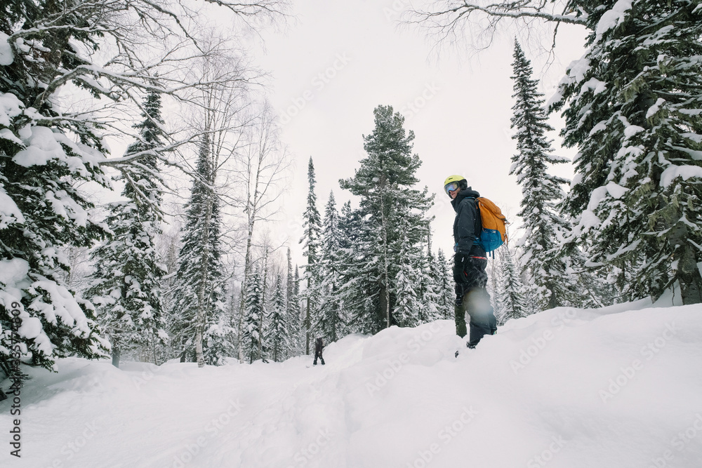 Freerider snowboarder standing in winter snow-covered forest, deep snow powder